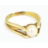 A yellow metal and pearl ring, the central pearl flanked by open claws, size N, approx 4.3g.