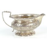 A George IV hallmarked silver cream jug of squat circular form with gilt washed interior, acanthus