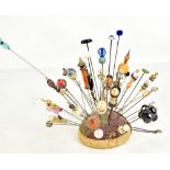 A collection of lady's hat pins of various sizes and form, with a pin cushion.Additional