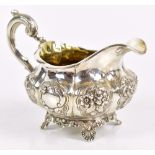 A William IV hallmarked silver cream jug with panels of floral embossed decoration, twin vacant