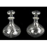 A pair of early/mid-20th century clear glass scent bottles and stoppers, with white metal overlay of