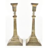 BRITTON, GOULD & CO; a pair of George V hallmarked silver candlesticks of plain form with cast