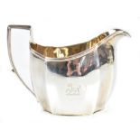 A George III hallmarked silver cream jug of panelled oval form, with simple loop handle and engraved