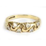 A 9ct yellow gold dress ring with swirling design set with six clear stones, size P, approx 2.4g.