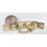 Seven hallmarked silver napkin rings, a hinged snap bangle, a small pin tray, a baby's push and a