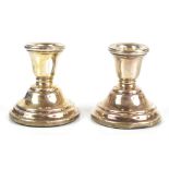 SANDERS & MCKENZIE; a pair of Elizabeth II hallmarked silver candlesticks of squat form,