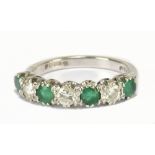 An 18ct white gold emerald and diamond seven stone ring, the three diamonds totalling approx 0.