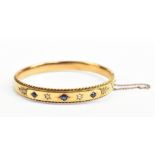 A 15ct yellow gold hinged snap bangle with three sapphires and two diamonds to the raised