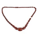 A string of graduated cherry amber beads, length 62cm, the largest bead 2.7 x 2cm, the smallest bead