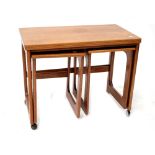 A retro teak nest of three tables, the largest with folding top and raised on castors,