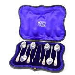 An Edward VII silver teaspoon and tong set, handles engraved in a Classical manner,