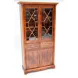 A reproduction bookcase with dentil moulded cornice above pair of astragal glazed doors flanked by