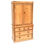 A pine linen press of small proportions with pair of panel doors enclosing three adjustable shelves