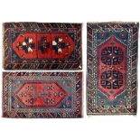 Three similar red ground hand-knotted woollen rugs, approx 120 x 70cm (3).