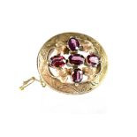 A yellow metal oval brooch with Art Nouveau and leaf decoration set with five amethysts, length 4.