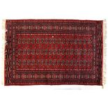 An Eastern red ground carpet with central panel surrounded by stepped geometric border,
