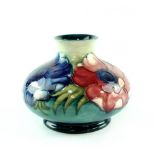 A Moorcroft squat baluster vase, blue green ground with tube lined anemone decoration,