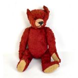 An early 20th century red plush teddy bear, length 36cm.Additional InformationGeneral wear, slight