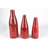 GARY HOLT; a graduated trio of porcelain bottles covered in mottled copper red glaze, incised marks,