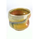 CHRIS GUSTIN (born 1969); an altered porcelain cup covered in shino glaze with streaks of blue,