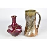 JIM CONNELL; a cut sided stoneware bottle covered in copper red glaze and a faceted salt glazed mug,