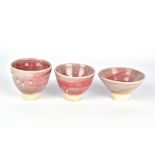 CLAYTON AMEMIYA; a group of three stoneware sake cups washed in copper red glaze, incised CA