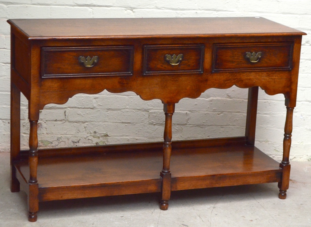 A reproduction oak dresser base with three drawers above under-tier on turned supports, height 89cm,
