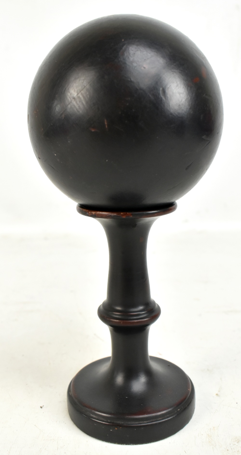 A mid 20th century ebonised ball on turned wooden stand, diameter of ball approx 11cm, overall