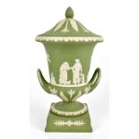 WEDGWOOD; a 20th century green jasperware twin handled lidded pedestal urn, decorated with figures