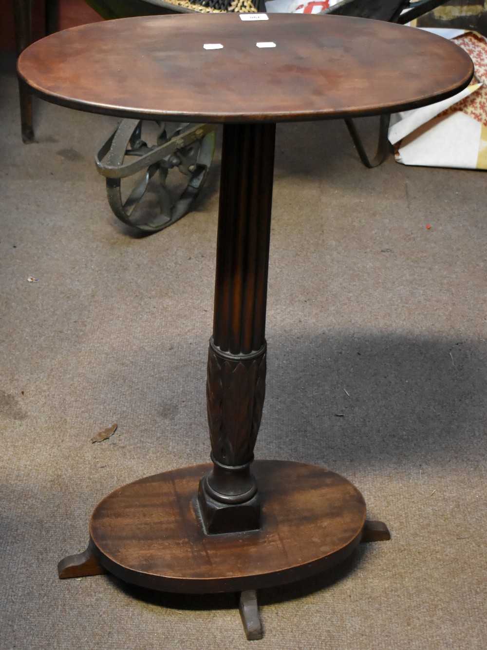 A mahogany and stained beech two tiered occasional table with oval top on fluted central stem and