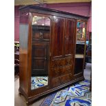 An early 20th century mahogany wardrobe with twin central panelled doors enclosing rail and fitted