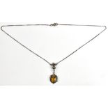 A silver scroll motif pendant set with oval cut yellow glass stone on curb link chain, length of