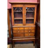 A Victorian mahogany cabinet on stand, the upper section with twin glazed doors enclosing two