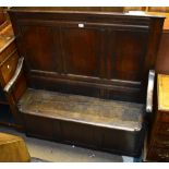 A late 18th century oak box seat settle with triple panelled back, swept arms, sliding seat and