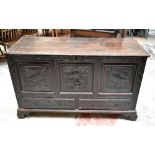An 18th century carved panelled oak coffer, the front with stylised carved detail of birds and