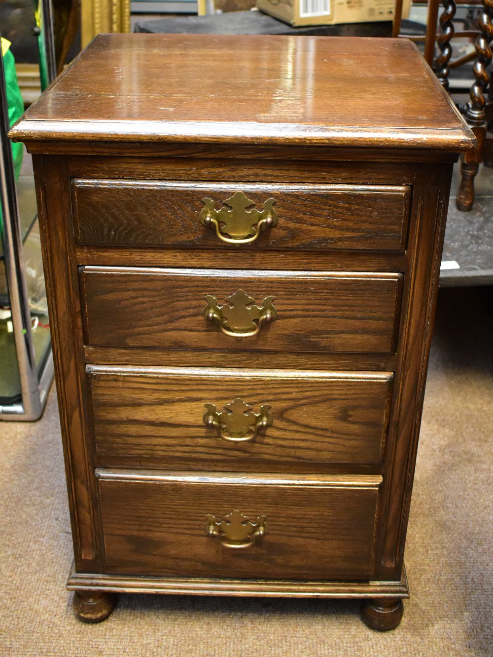 REPRODUX; a reproduction narrow oak chest of four drawers, raised on bun feet, height 69cm, width