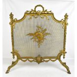 An early 20th century ornate brass fire screen with central mesh section raised on four angled swept