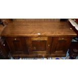 A reproduction oak miniature sideboard, the central door enclosing two shelves with storage