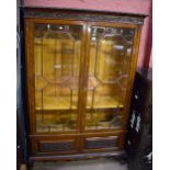 An early 20th century oak display cabinet with floral detailed frieze above twin astragal glazed