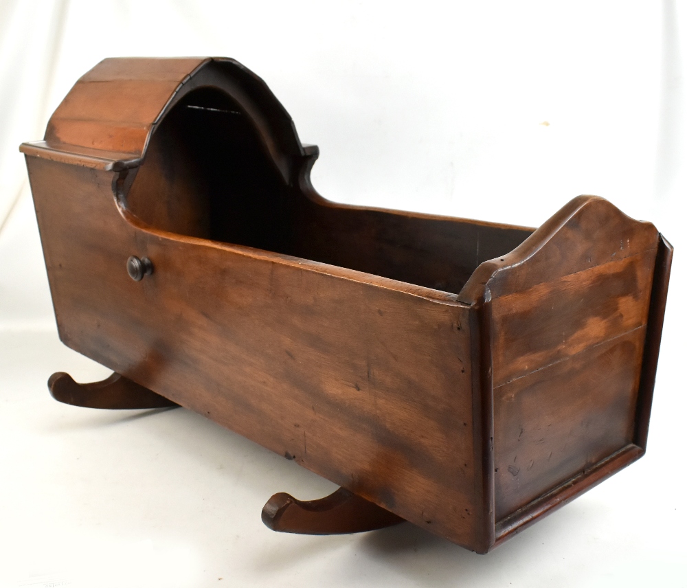 An early 20th century and later stained mahogany and pine child's rocking crib with arched partial