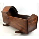 An early 20th century and later stained mahogany and pine child's rocking crib with arched partial