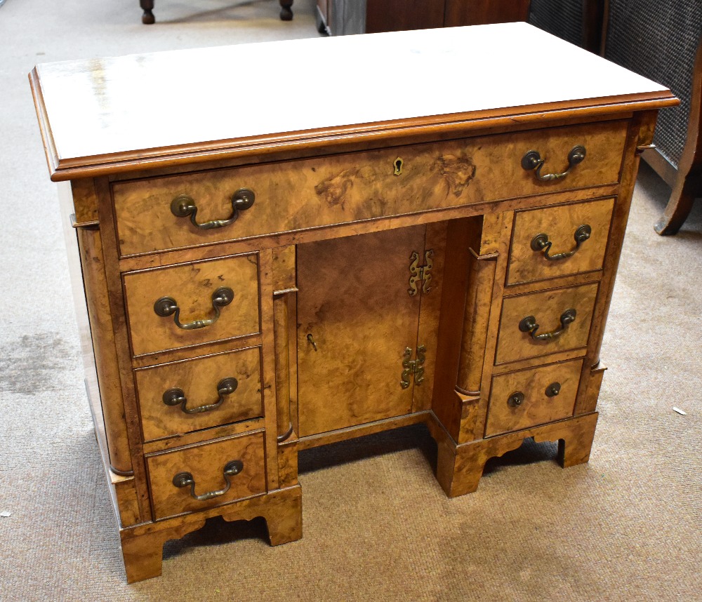 A reproduction burr walnut veneered knee hole desk with single long drawer above six short drawers