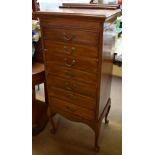 An Edwardian mahogany music cabinet with raised back above seven graduated drawers with fold down