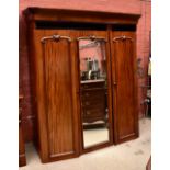 A Victorian mahogany triple wardrobe with moulded cornice above central mirrored door with hanging