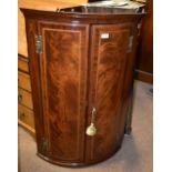 A George III mahogany satinwood and boxwood strung bowfronted corner cupboard with brass H hinges