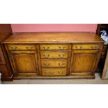 A reproduction oak sideboard with cross banded detail and four central drawers flanked by two