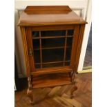 An Edwardian mahogany music cabinet, the glazed door enclosing three shelves above undertier on