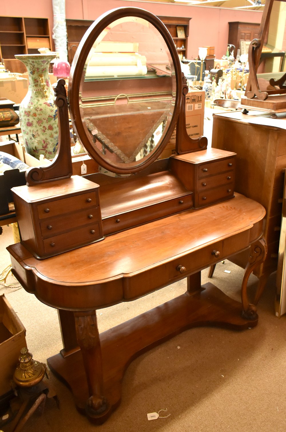 A Victorian mahogany dressing table with oval mirror above arrangement of seven drawers, the