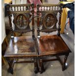 A pair of 19th century Continental oak hall chairs, the back panels with carved detail depicting
