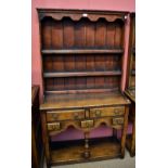 A small reproduction oak dresser, the plate rack back with two fixed shelves above an arrangement of